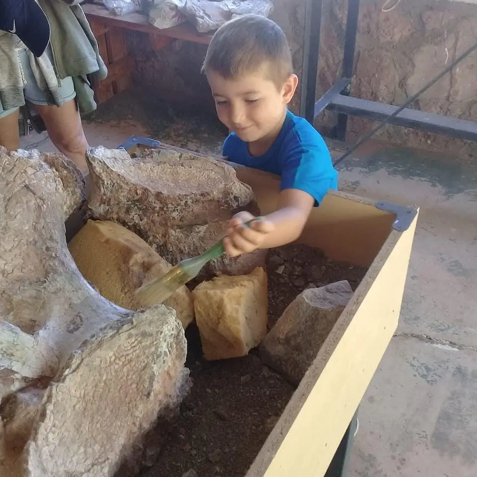 Nino_Limpiando Un niño limpiando fósiles con guia